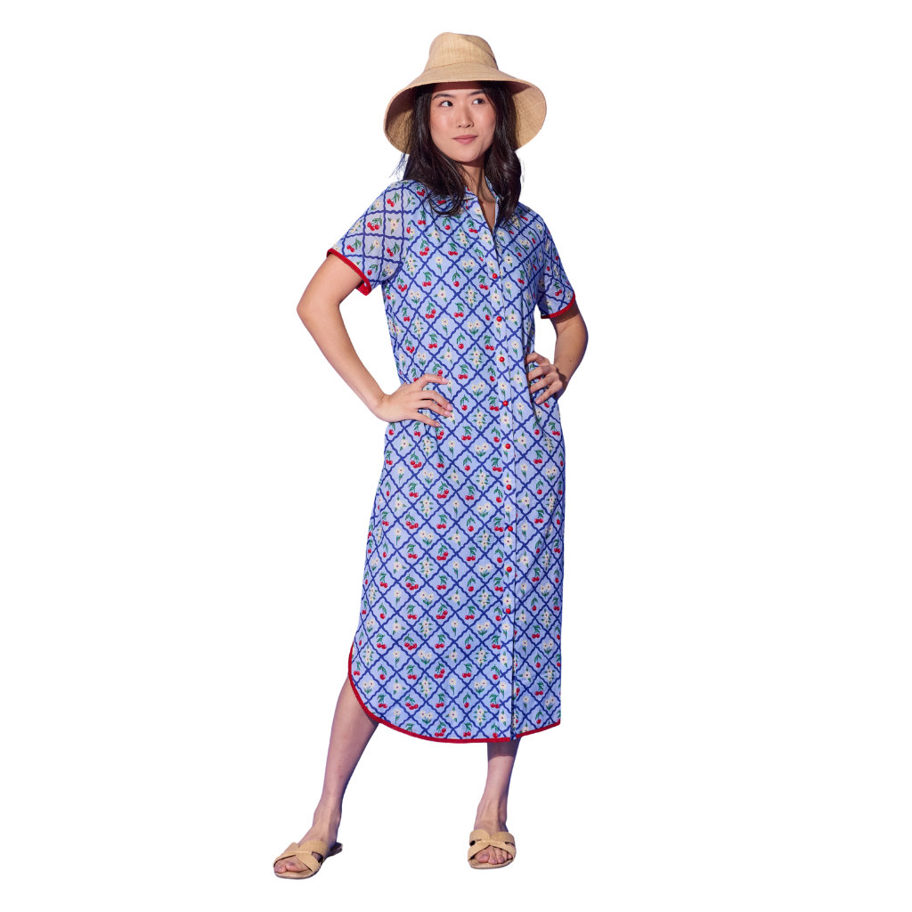 Woman wearing a blue patterned dress with a hat on a white background