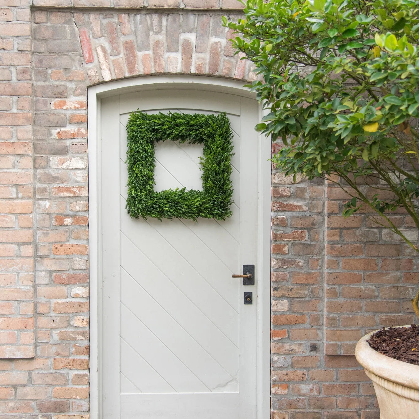 White door with a green wreath on a brick wall