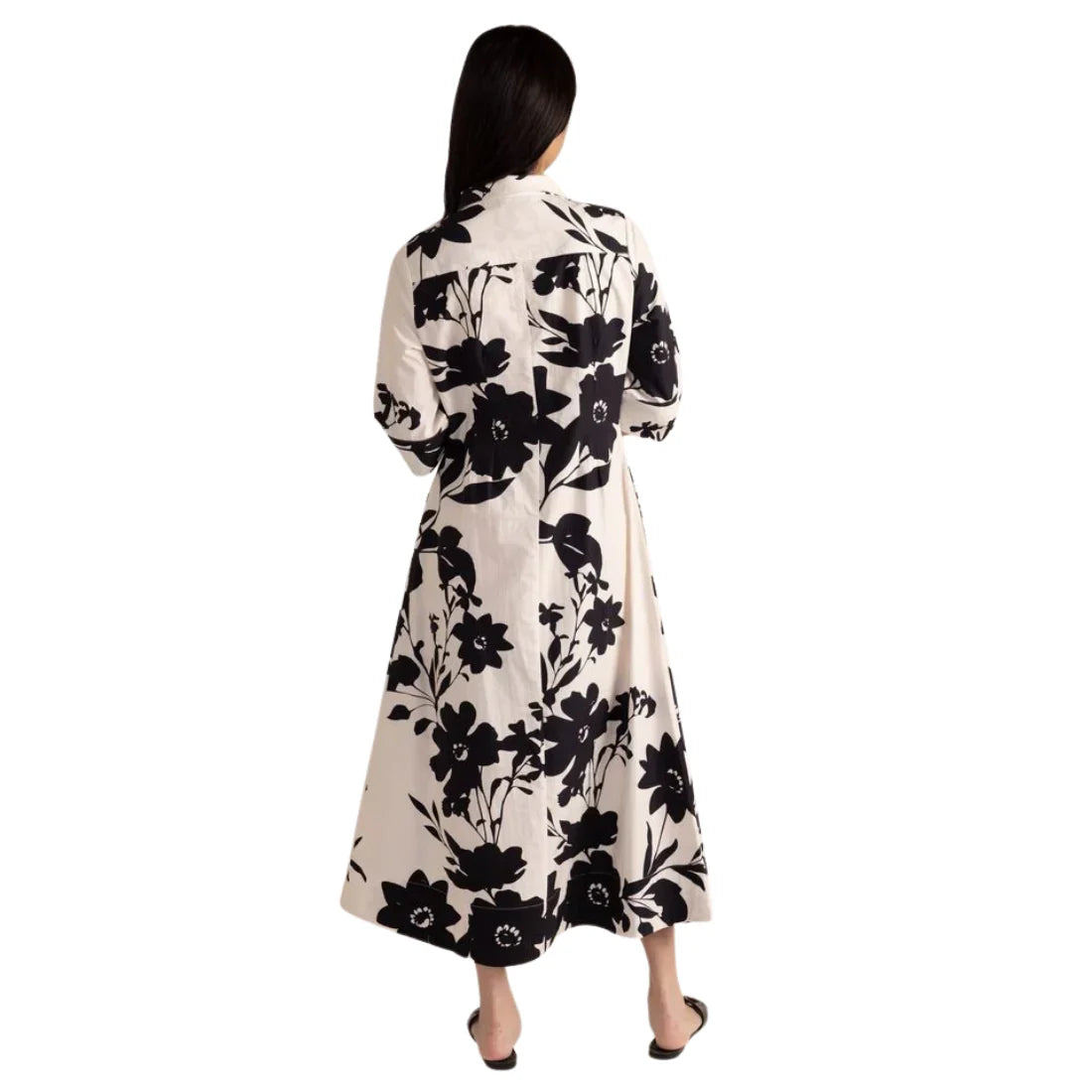 Woman wearing a long floral dress with black flowers on a white background