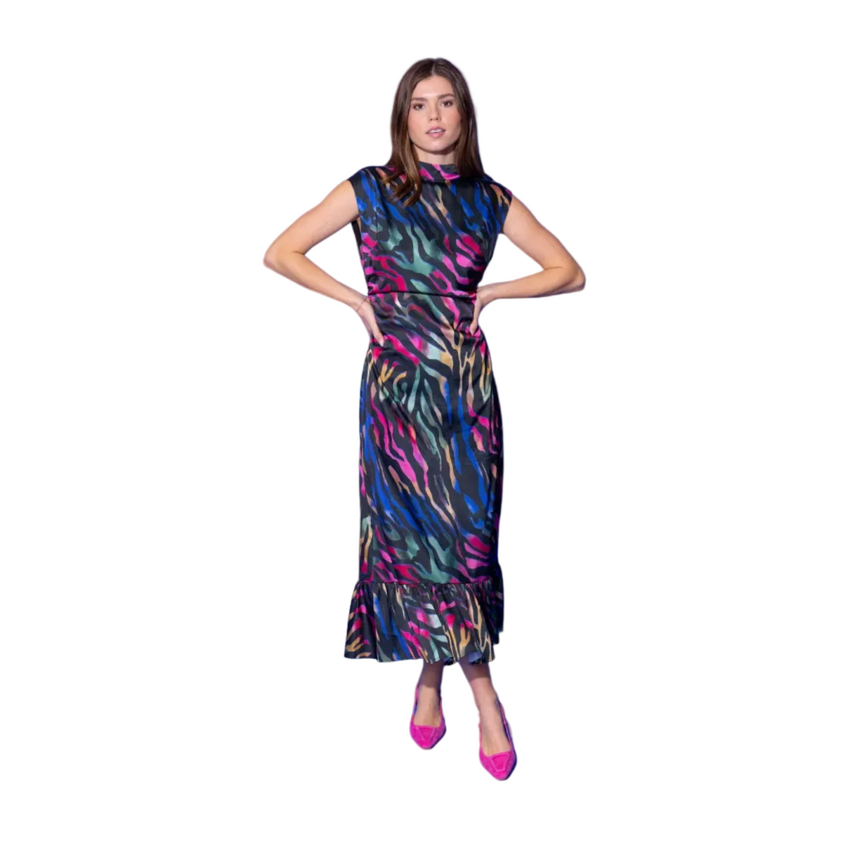 A woman modeling a sleeveless, high-neck midi dress with a colorful abstract print in pink, green, blue, and yellow on a black base, paired with bright pink heels, set against a solid blue studio background.