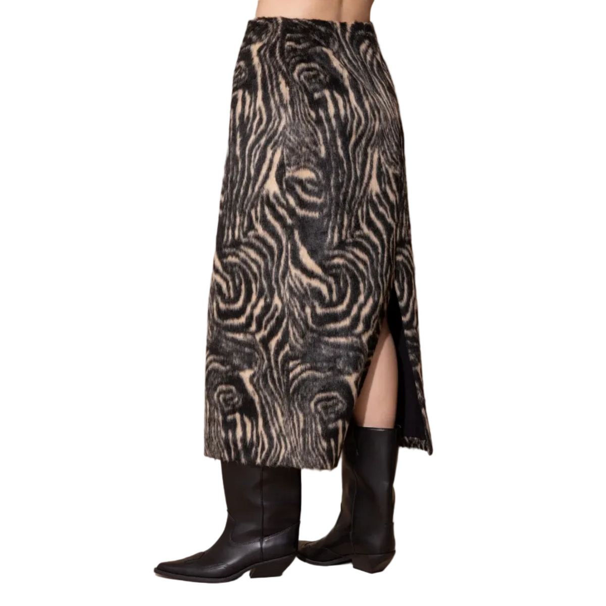 A high-waisted midi skirt with a black and beige zebra-like swirl pattern, featuring a side slit and worn with black cowboy boots against a solid beige background.