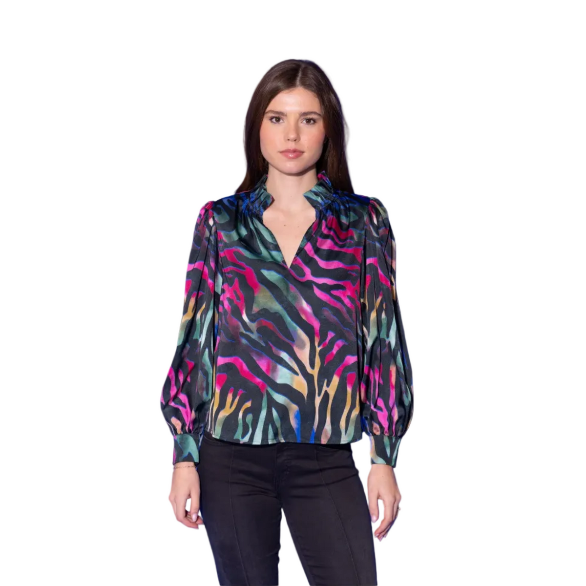 A woman modeling a long-sleeve satin blouse with a vibrant multicolor abstract print, paired with black pants, set against a solid blue studio background.
