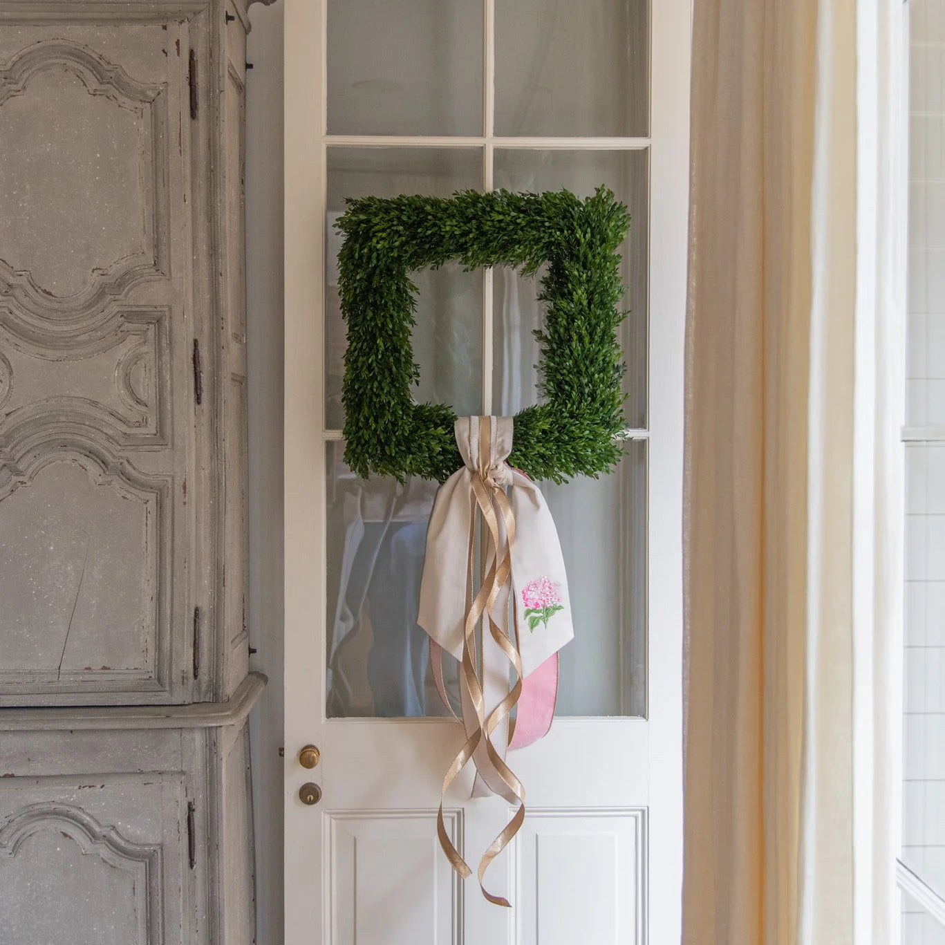 Green wreath with a ribbon on a white door