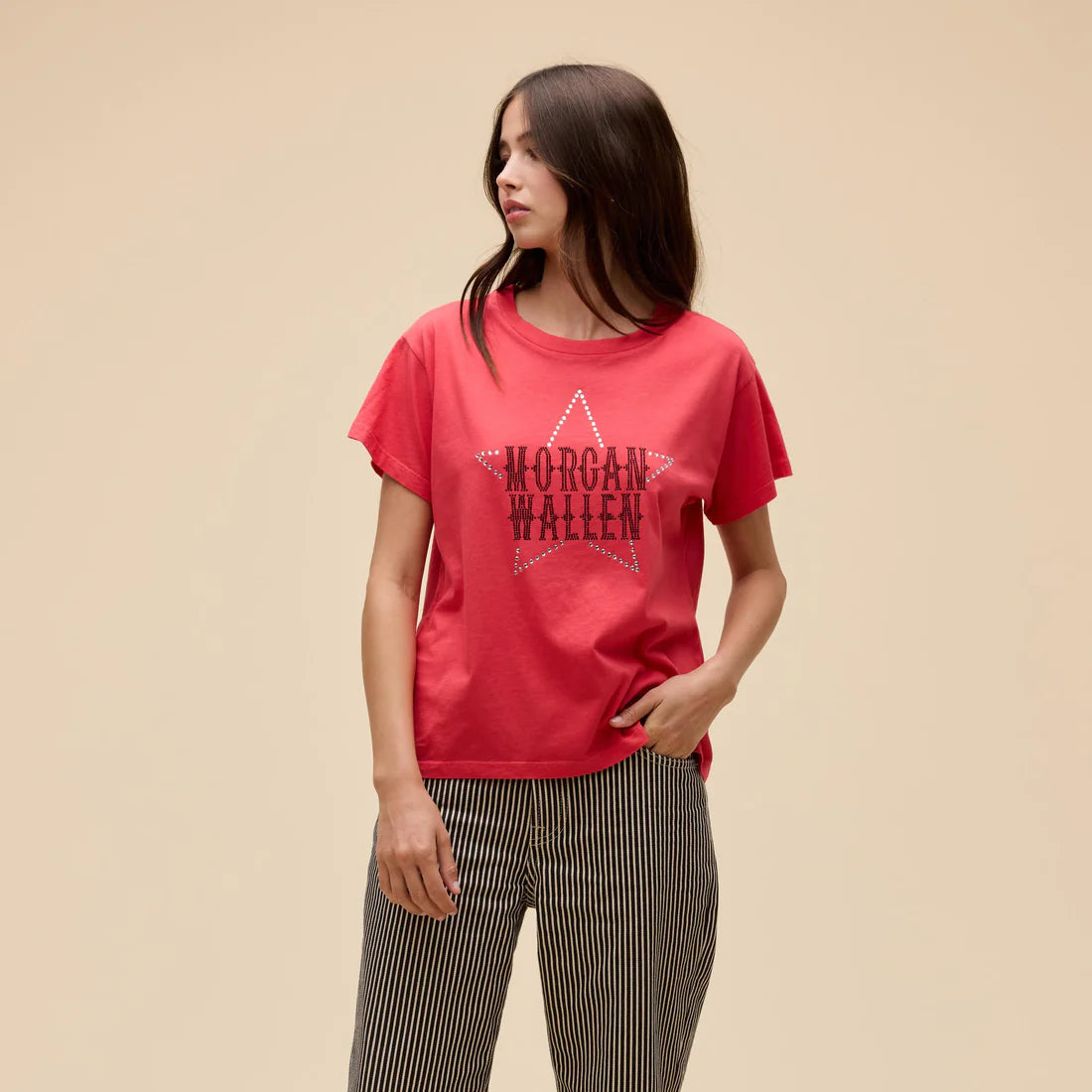Person wearing a red t-shirt with a graphic design on a beige background