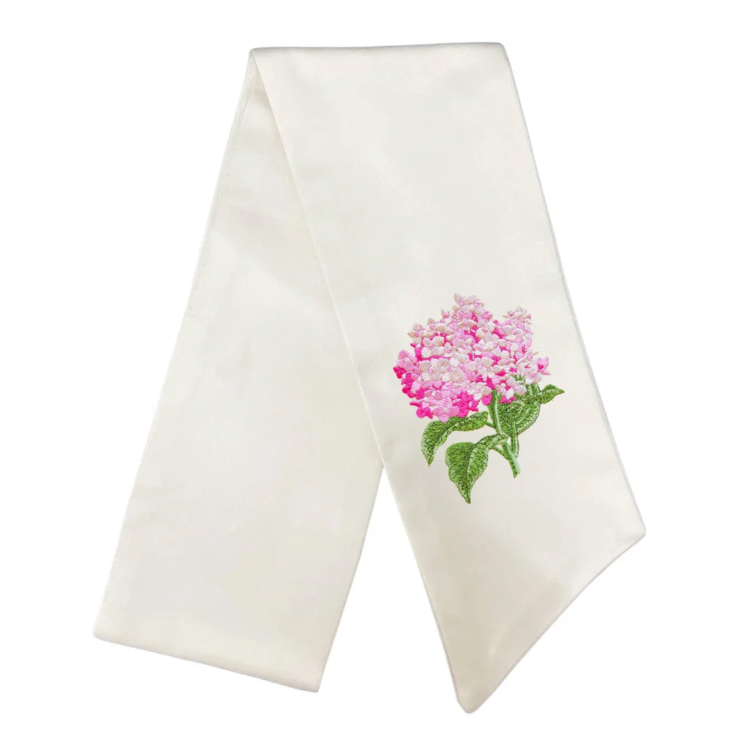 An off-white satin or silk church veil featuring an embroidered pink hydrangea with green leaves on the right side, displayed against a solid white background.