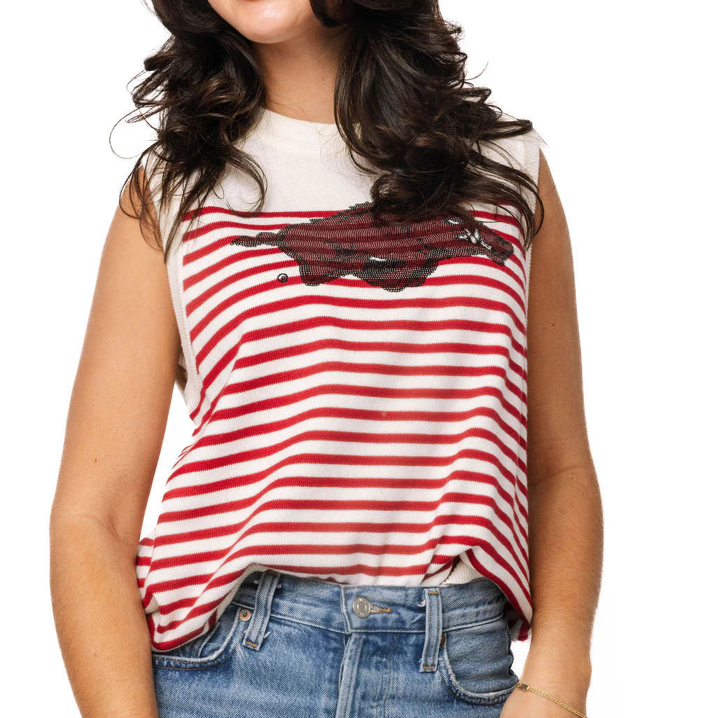 Woman wearing a red and white striped tank top with a graphic design, paired with blue jeans on a white background.