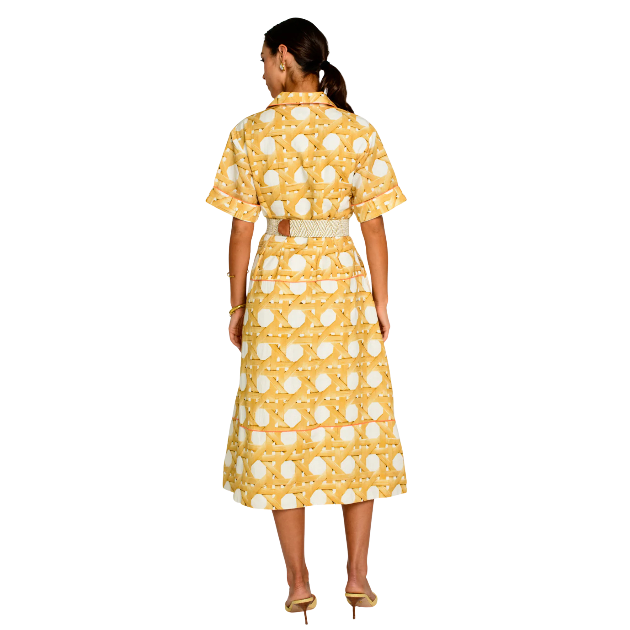 A woman viewed from the back wearing a yellow and white patterned midi dress with short sleeves and a matching belt, paired with gold heels against a plain white background.