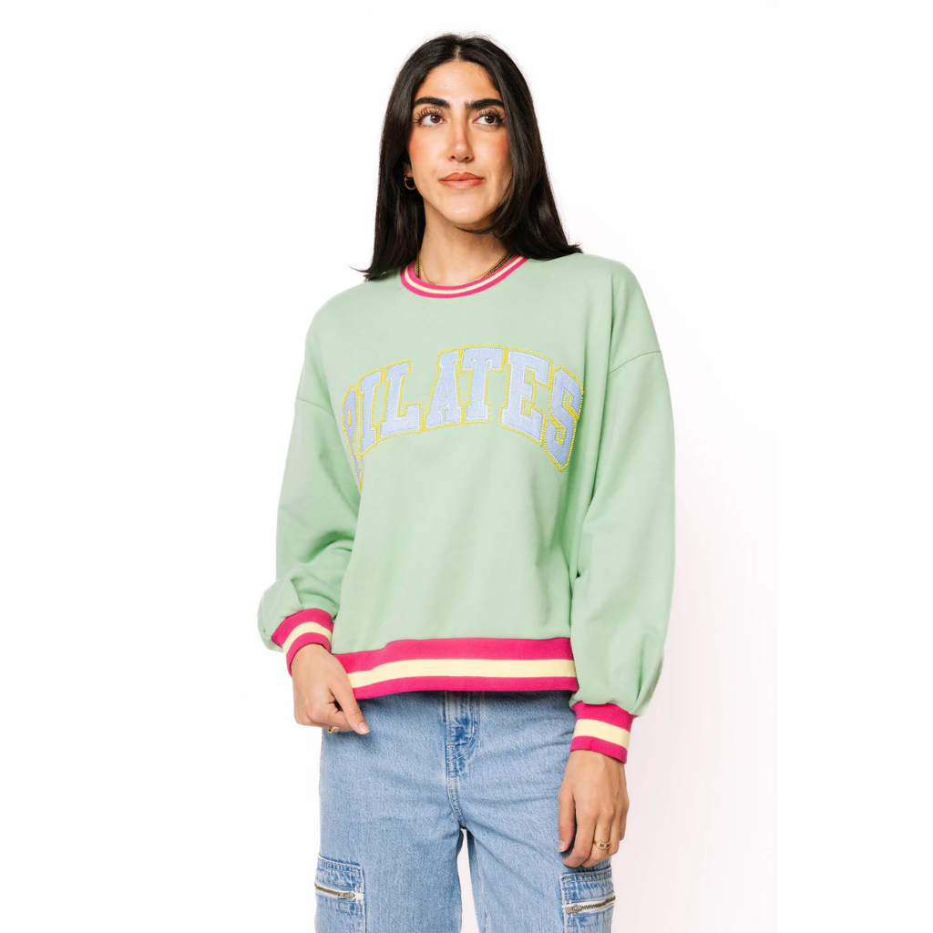 Woman wearing a light green sweatshirt with colorful trim on a white background