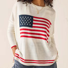 Person wearing a sweater with an American flag design on a plain background