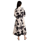 Woman wearing a long floral dress with black flowers on a white background