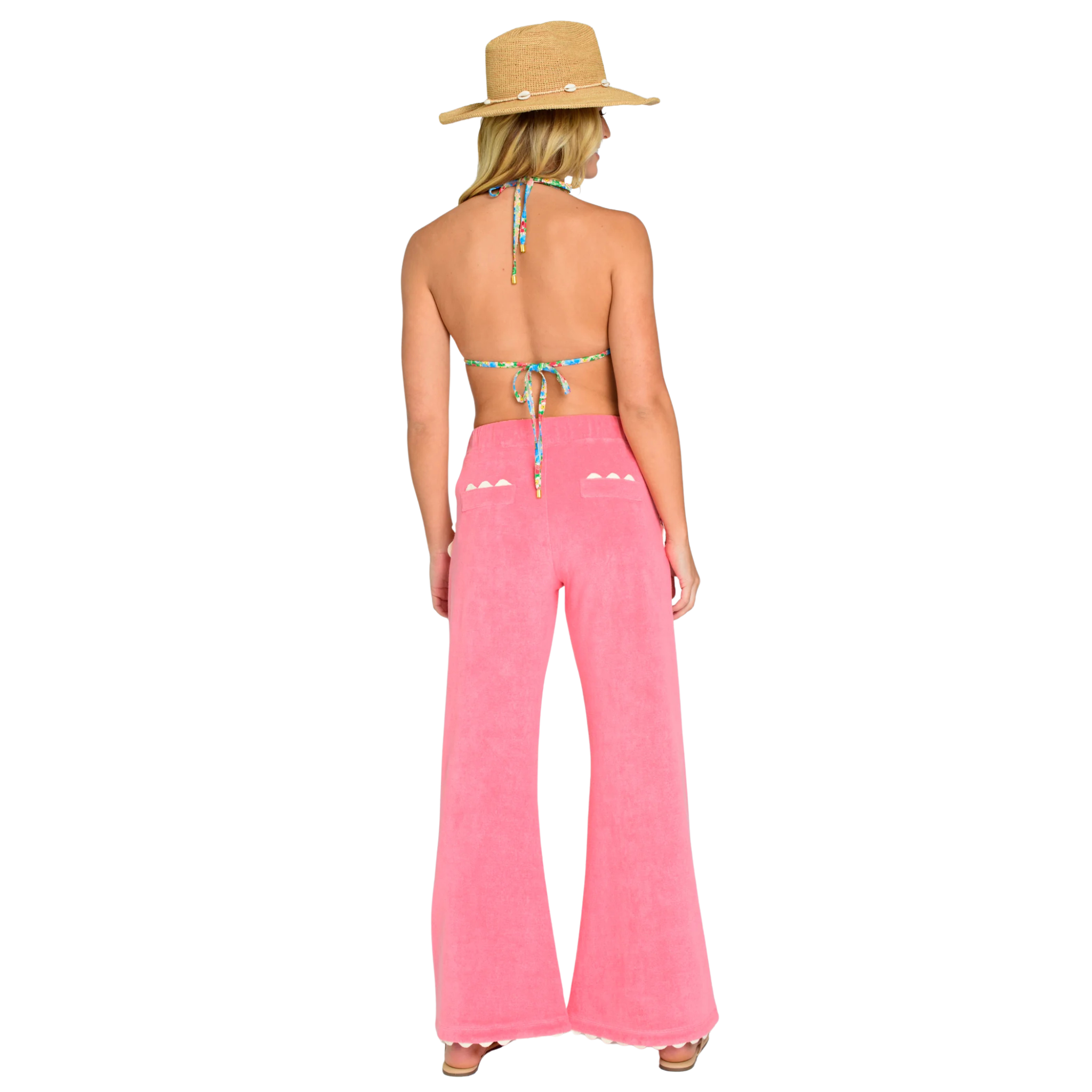 Woman wearing a pink jumpsuit with a straw hat on a white background