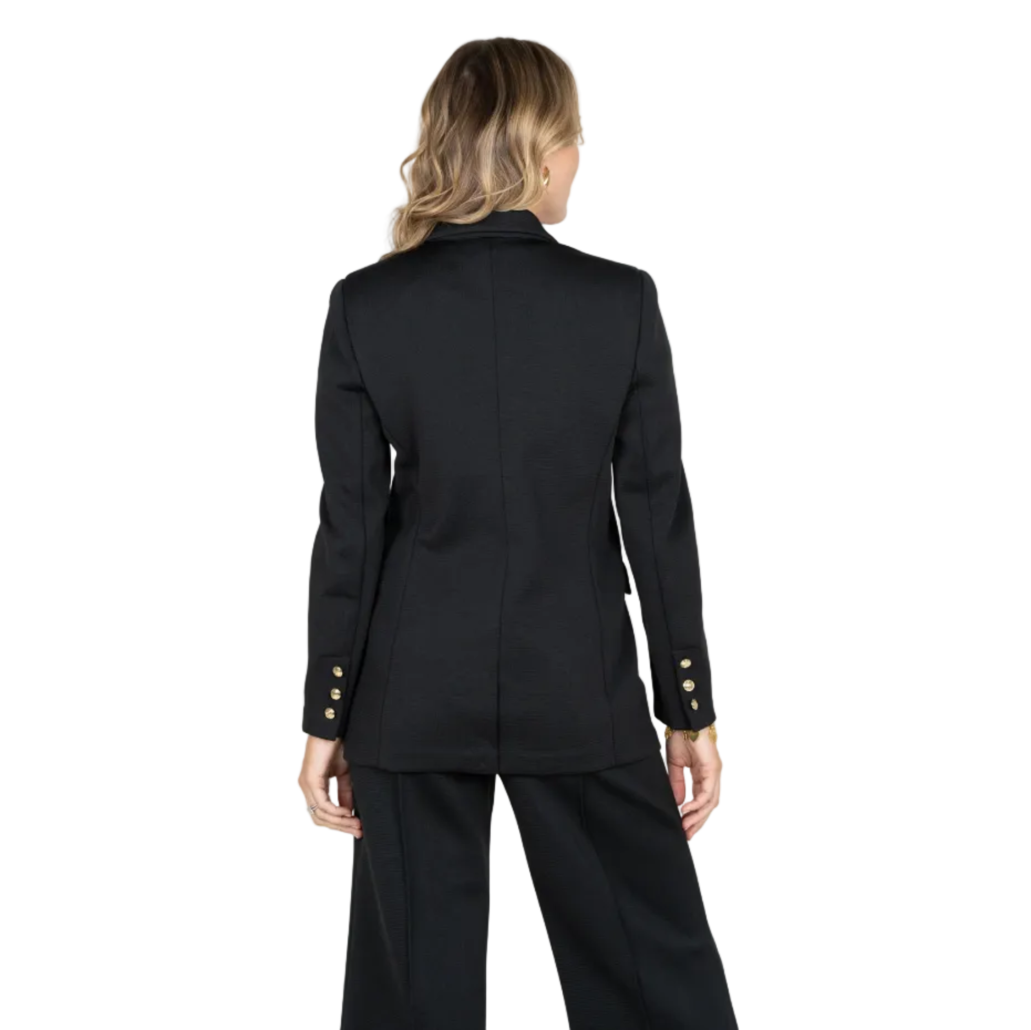 A woman shown from the back wearing a black tailored blazer with gold button accents on the sleeves and matching black trousers, photographed against a light gray studio background.