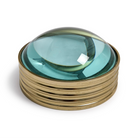 A vintage-style dome glass object with a translucent aqua blue glass dome resting on a polished gold-toned metal base, photographed on a clean white background.