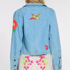 Light blue denim jacket with colorful floral embroidery on a plain background