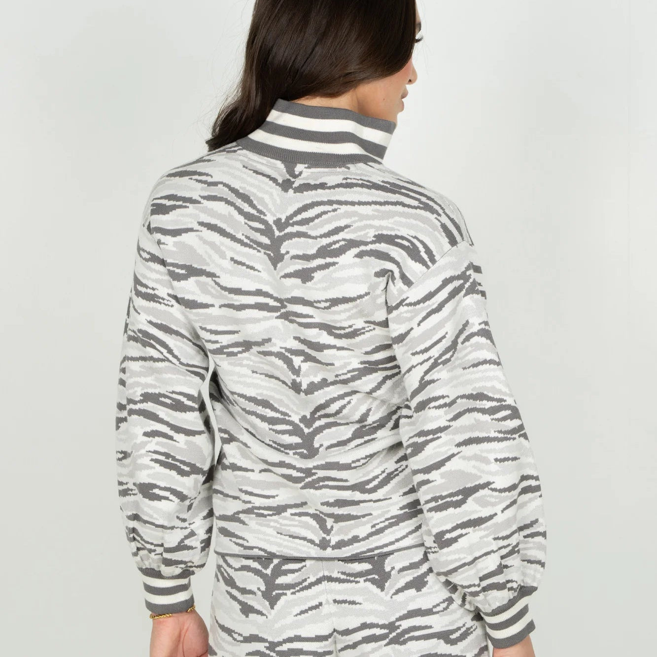The Lolli Sweater in Wild Marble features a stand collar, notched neckline, and blouson sleeves finished with striped trim at the neckline and cuffs. The relaxed silhouette showcases our Wild Marble print, reimagining the marble veining found throughout Roman architecture as a tiger stripe motif in layered shades of grey. 