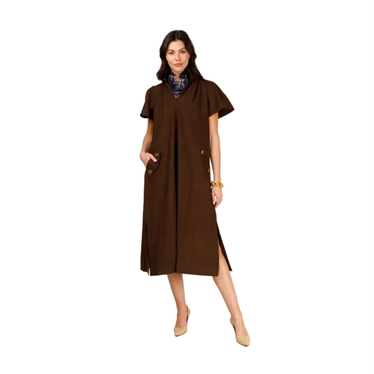 A woman modeling a brown short-sleeve midi dress with a high collar, front pockets, and side slits, styled with a patterned scarf and beige heels against a light gray studio background.