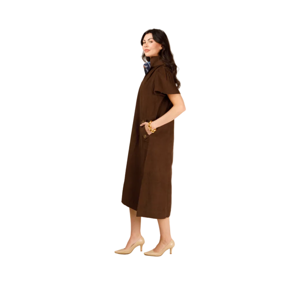 A woman modeling a brown short-sleeve midi dress with a draped collar and side pockets, paired with beige heels, against a light gray studio background.