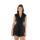 A woman modeling a black sleeveless wrap-style top with matching shorts against a plain light gray studio background.