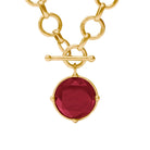 Gold chain necklace with a round faceted red gemstone pendant in a gold bezel setting and toggle clasp, shown on a white background.