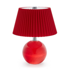 A modern table lamp featuring a pleated red fabric shade and a glossy red glass spherical base, set against a plain white background.
