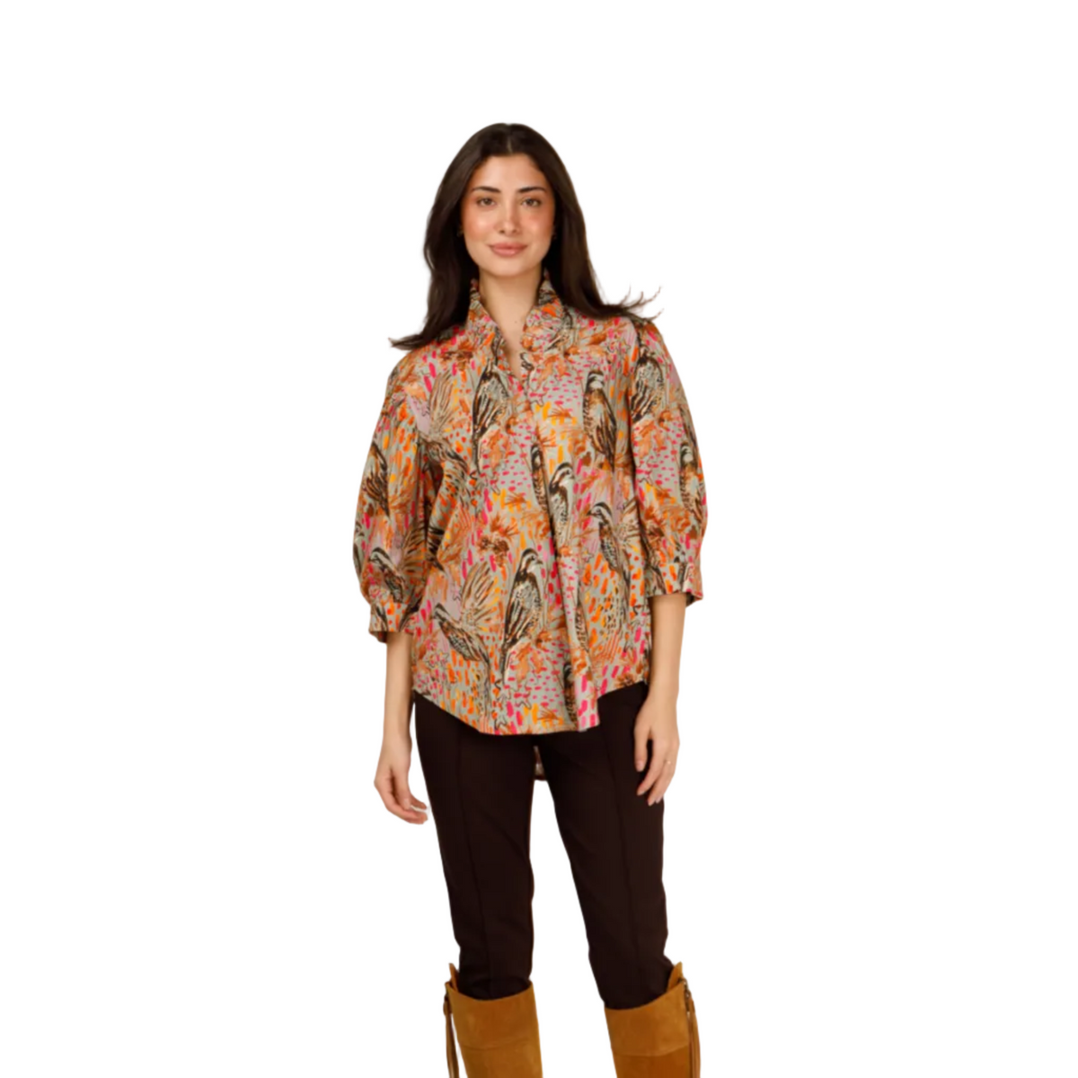A woman modeling a colorful bohemian-style patterned blouse with puff sleeves, paired with dark brown pants and tan suede knee-high boots, against a plain white studio background.