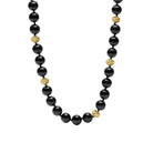 A beaded necklace featuring glossy black round beads and textured gold spacer beads, displayed on a clean white background.