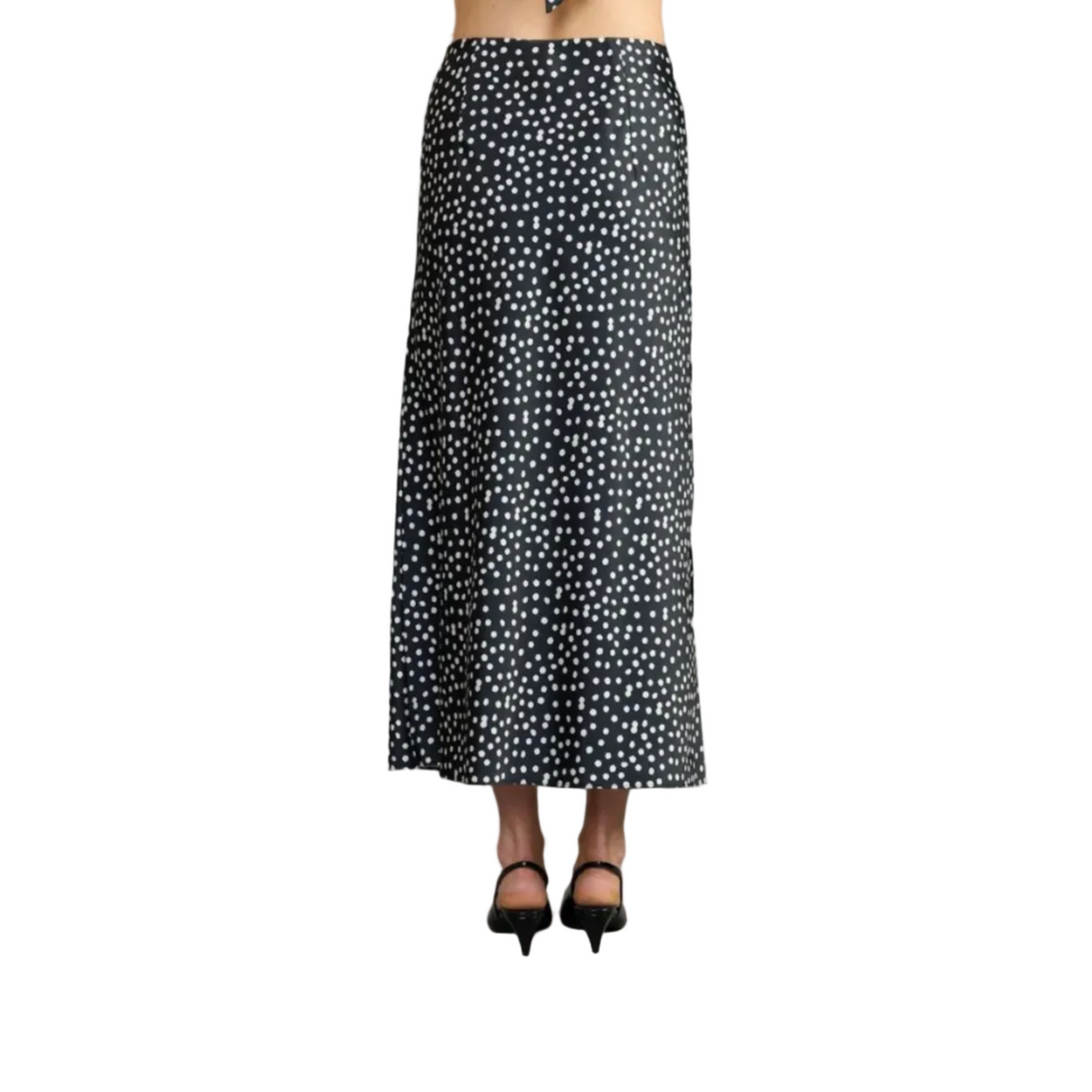A black midi skirt with a white polka dot pattern, shown on a model from the waist down wearing black high heels against a solid gray studio background.