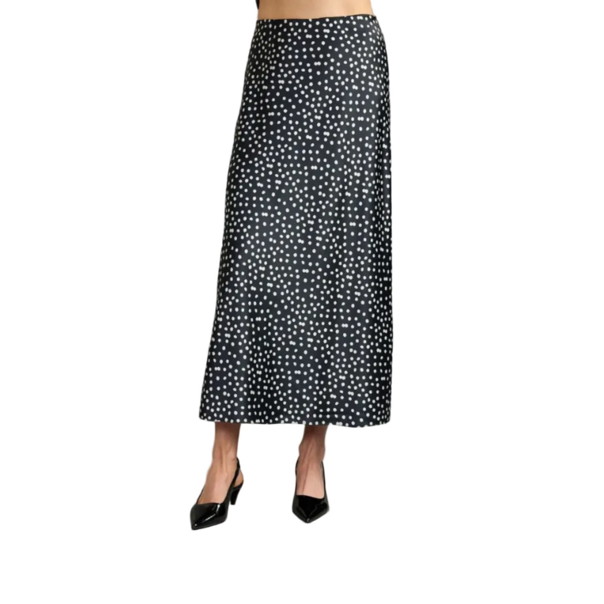 A black midi skirt with a white polka dot pattern, shown on a model wearing black pointed-toe heels against a solid gray studio background.