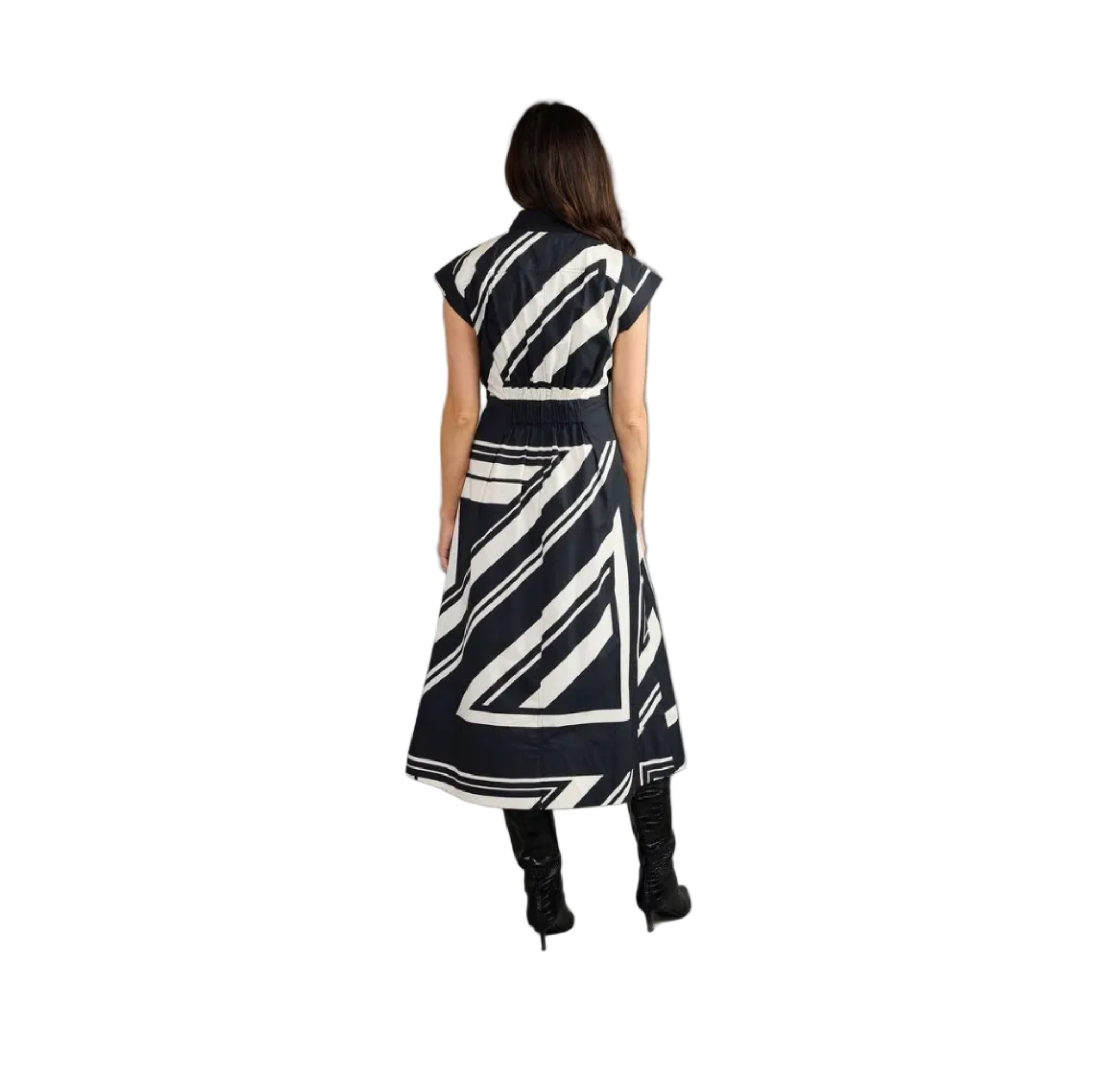 A woman viewed from behind wearing a sleeveless midi dress with a bold black and white abstract brushstroke pattern, paired with black pointed-toe heels, against a solid gray studio background.