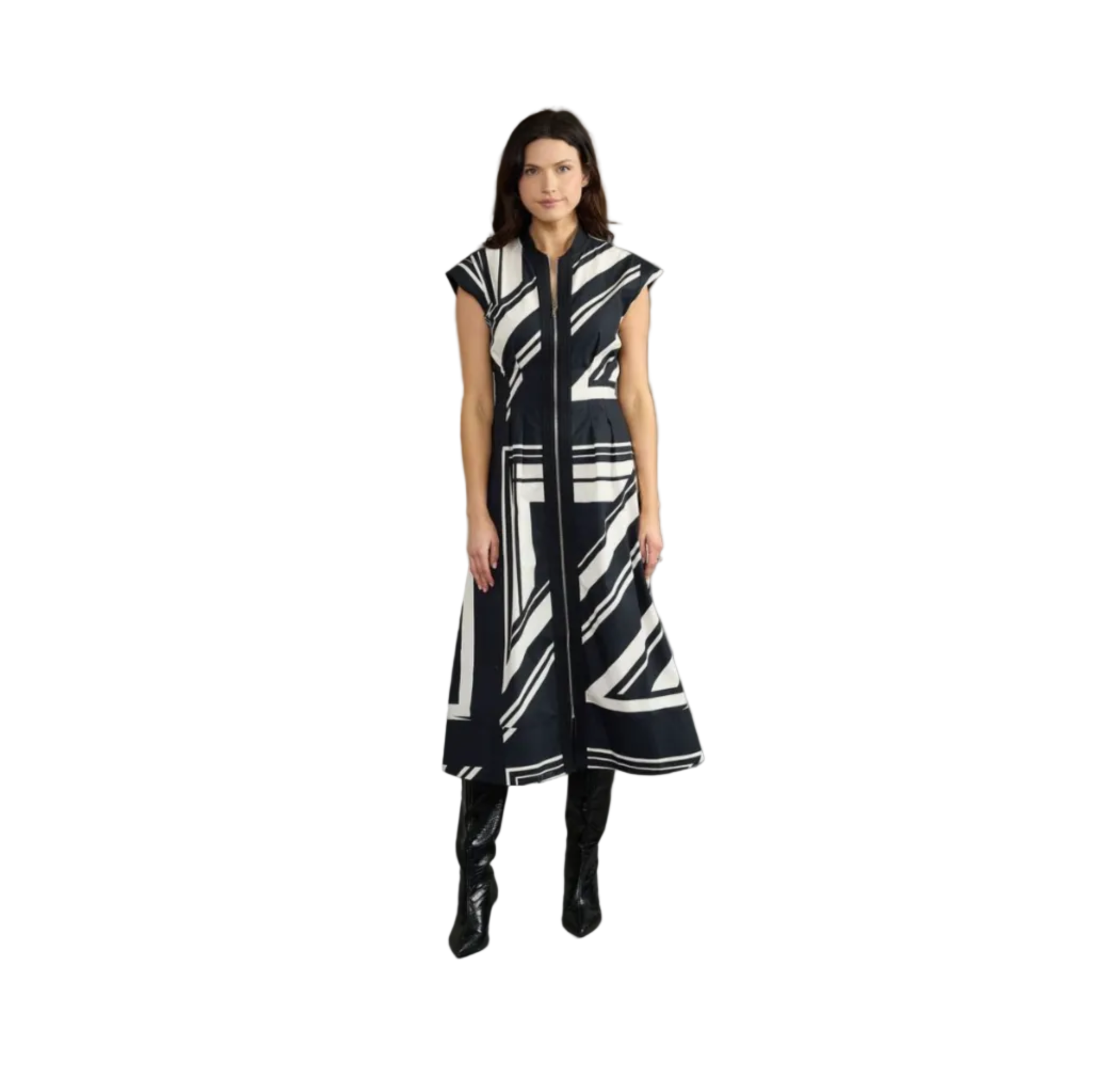 A woman modeling a sleeveless, midi-length black and white geometric patterned dress with a high collar and front zipper, paired with black knee-high boots, against a solid gray studio background.