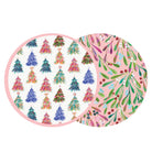 Two overlapping round decorative plates or platters with festive holiday patterns. One plate features colorful Christmas tree motifs on a white background with a pink border, and the other shows a pink background with green mistletoe and red berries.
