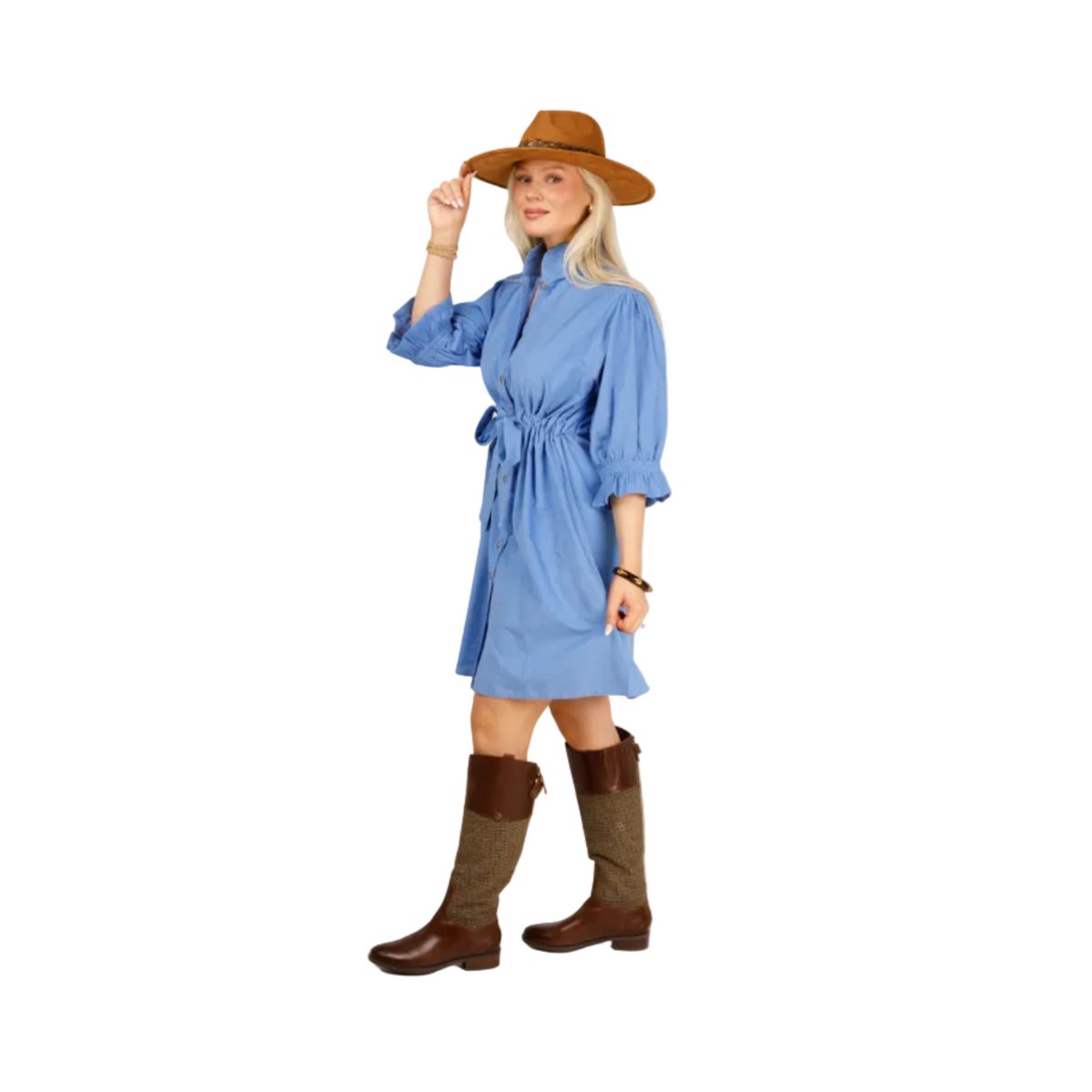 A woman modeling a light blue long-sleeve shirt dress with a tie waist, styled with a brown wide-brim hat and brown boots against a light gray studio background.