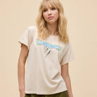 Woman wearing a beige t-shirt with a graphic design on a beige background