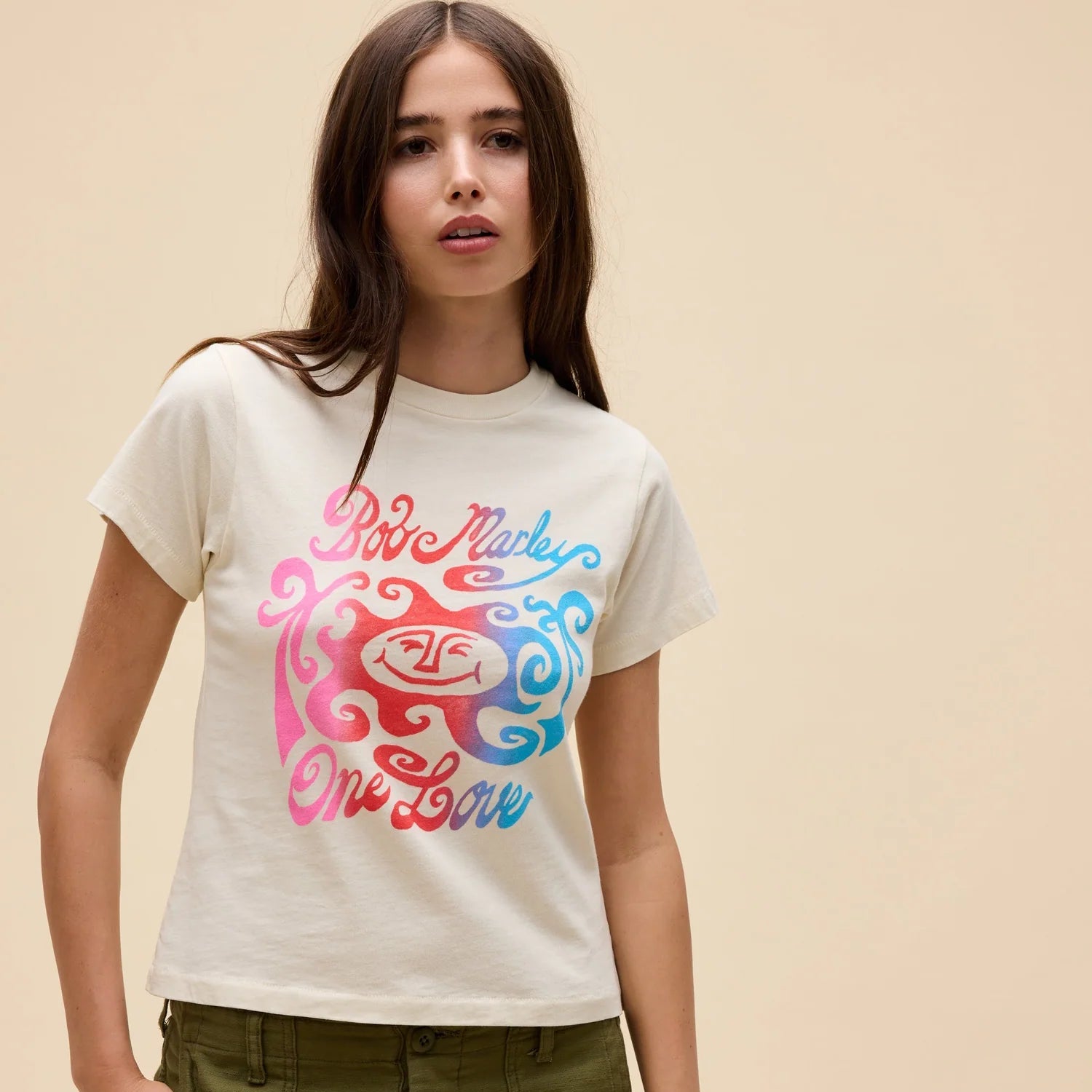 Woman wearing a white t-shirt with colorful graphic design on a beige background
