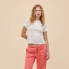 Woman wearing a white t-shirt and pink pants on a beige background