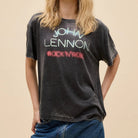 Person wearing a black t-shirt with 'John Lennon Rock 'N' Roll' text on a beige background