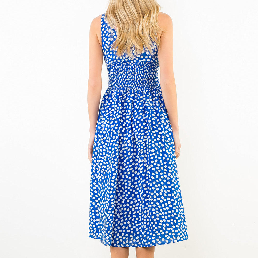 Woman wearing a blue dress with white floral pattern on a plain background